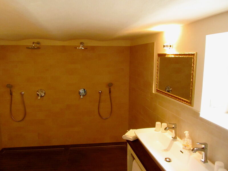 Modern bathroom with natural lime plaster, walk-in shower, and warm lighting