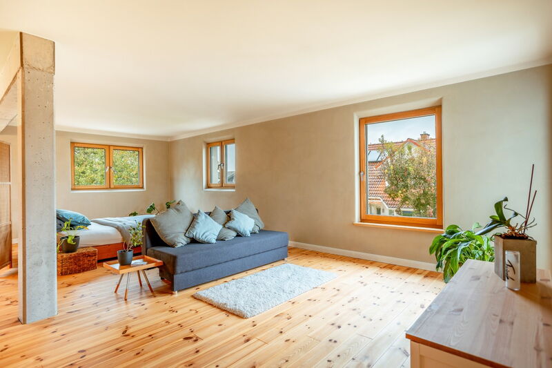 Bright living room with warm beige natural lime plaster, wooden floor and large windows