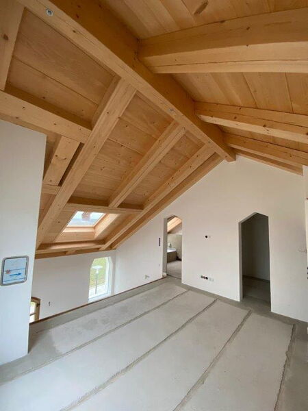 Attic conversion with exposed timber structure and interior walls finished with natural lime plaster