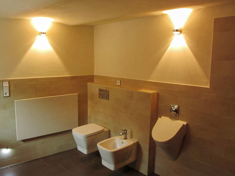 Modern bathroom with natural lime plaster, tiles and indirect wall lighting