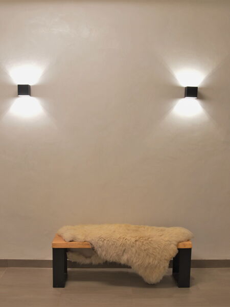 Plastered wall with natural lime plaster, two wall lights and bench