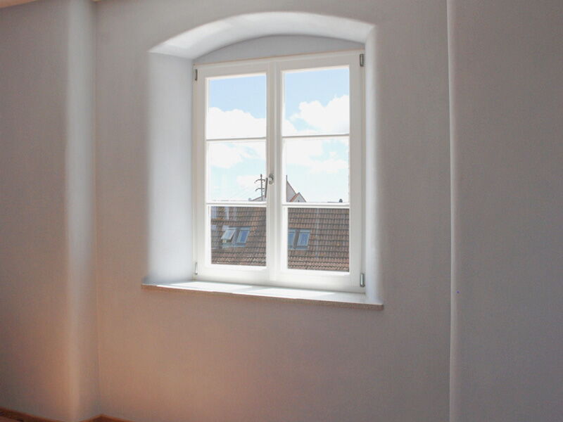 Arched window with white natural lime plaster and bright window reveal