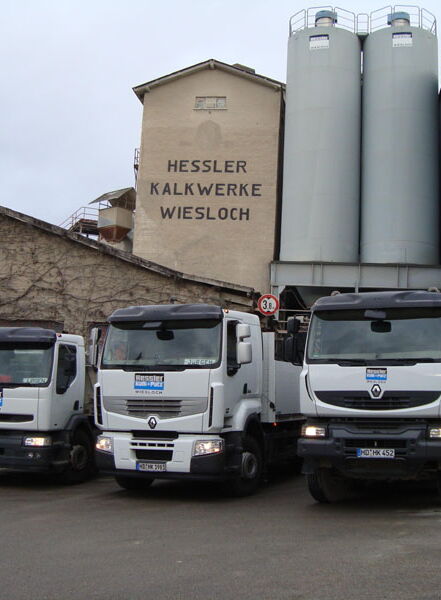 Truck fleet in front of the Hessler Kalkwerke plant with silos and loading area