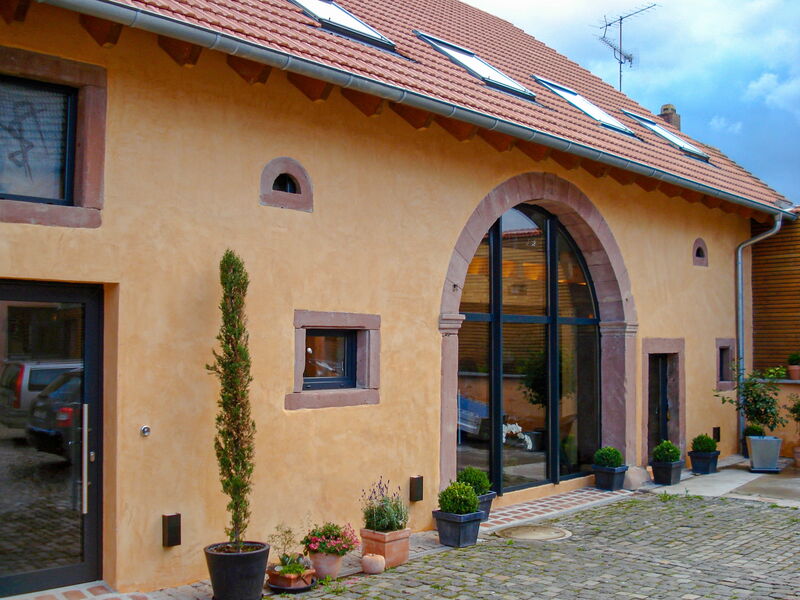 Renovated facade with natural lime plaster, arched entrance and natural stone surround