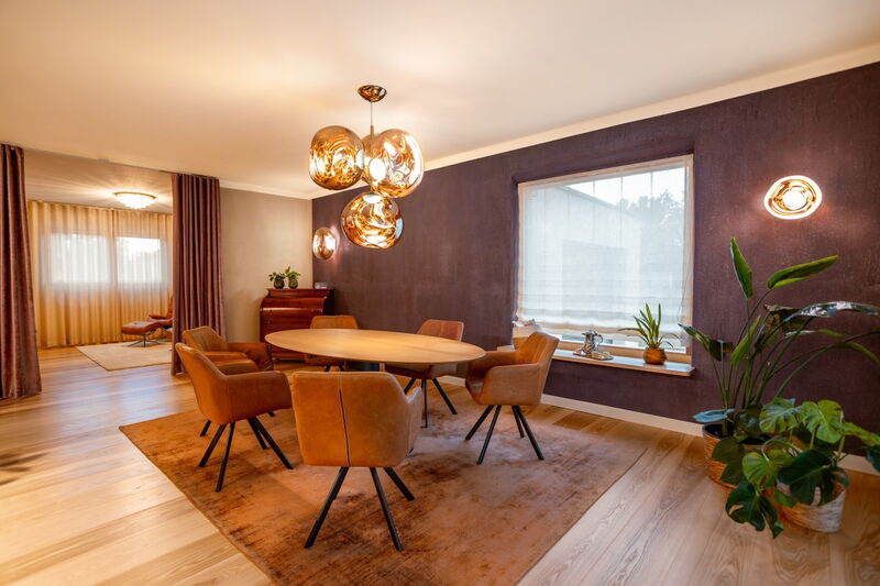 Modern dining area with dark natural lime plaster wall, wooden floor and glass pendant lights