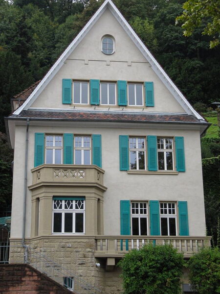 Renovated historic villa with natural lime plaster facade and green shutters