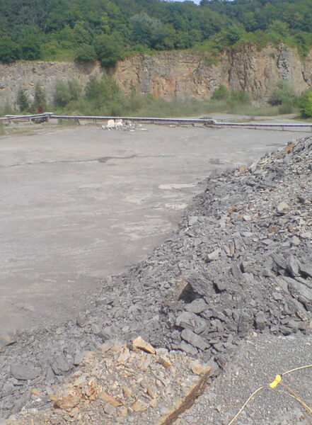 Extraction area in a limestone quarry with rock stockpile and quarry edge