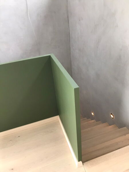 Stairwell with grey natural lime plaster, wooden steps and integrated stair lights
