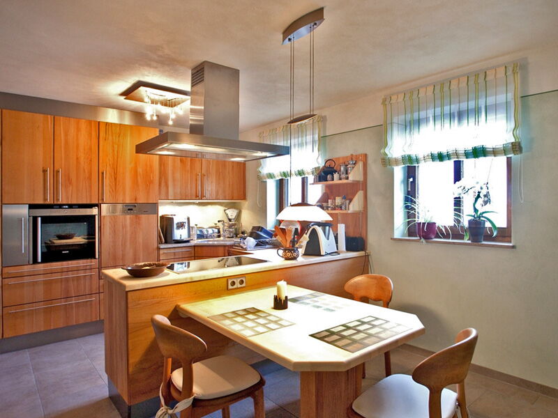Open-plan kitchen with dining area, wooden cabinetry and green natural lime plaster wall finish