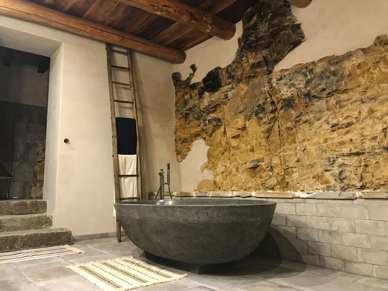 Bathroom with natural stone wall, freestanding bathtub and white natural lime plaster