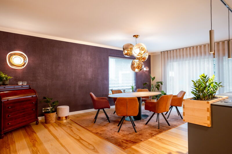 Modern living and dining area with dark natural lime plaster wall, wooden floor and designer lights