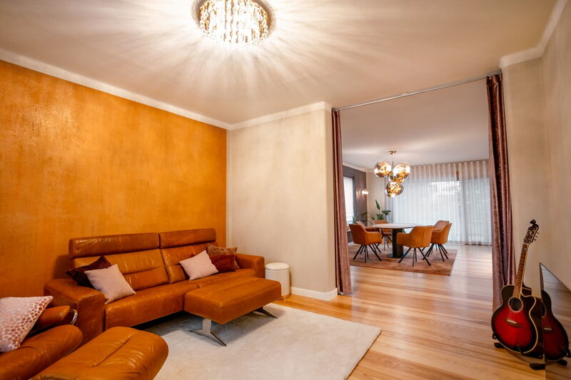 Living area with golden natural lime plaster, leather sofa and view into the dining area