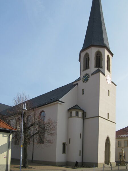 Church building with light natural lime plaster facade and clock tower